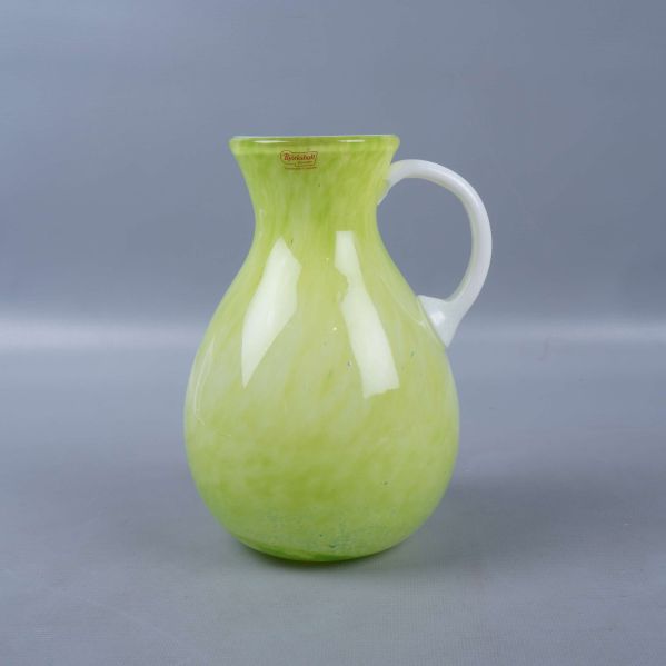 Grön vas med vitt handtag fotograferad framifrån