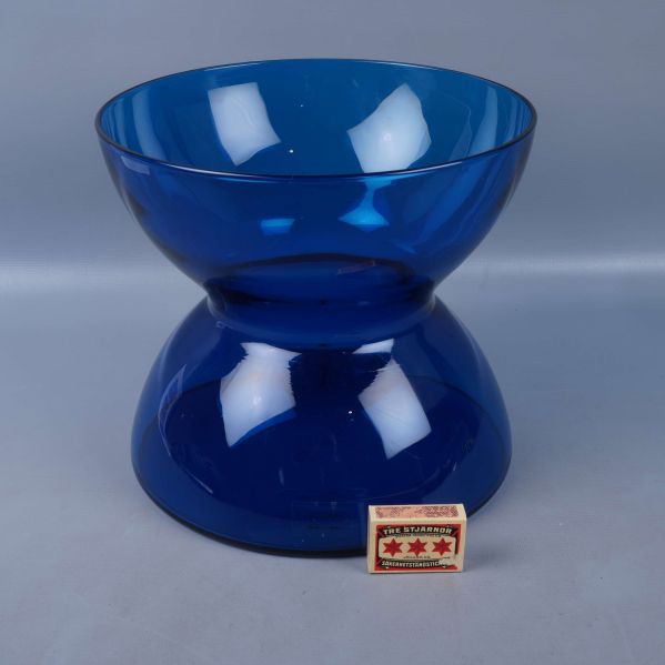 Blå glasvas framför tändsticksask för storleksjämförelse