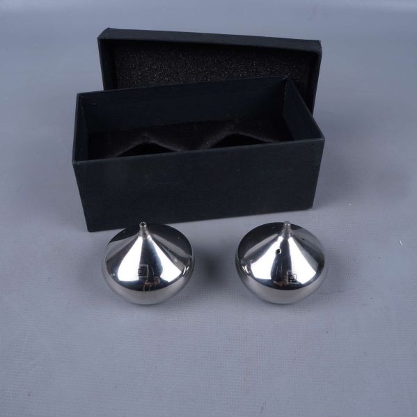 Två runda kryddströare bredvid svart ask