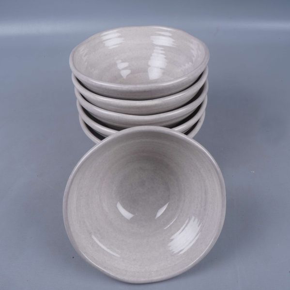 Sex ljusgrå skålar staplade och en vänd mot kameran
