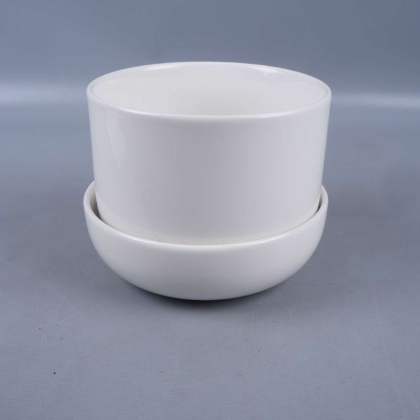 Vit rund kruka med fat mot grå bakgrund