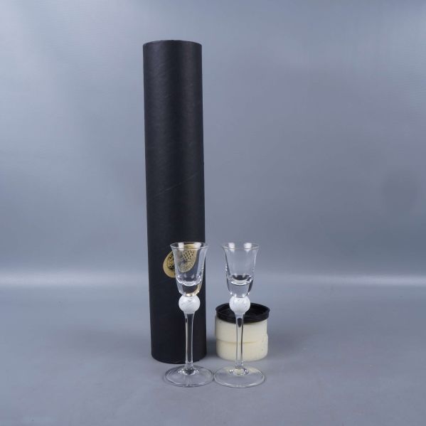 Två snapsglas med vit kula och svart förvaringsetui