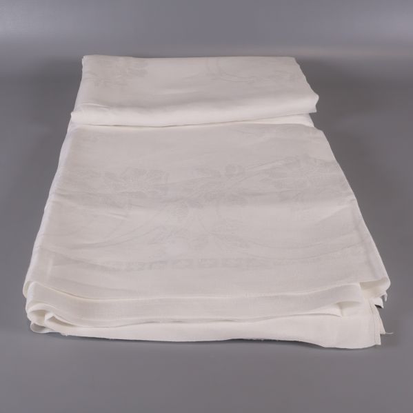 Uppvikt vit duk med synligt blomdetaljmönster