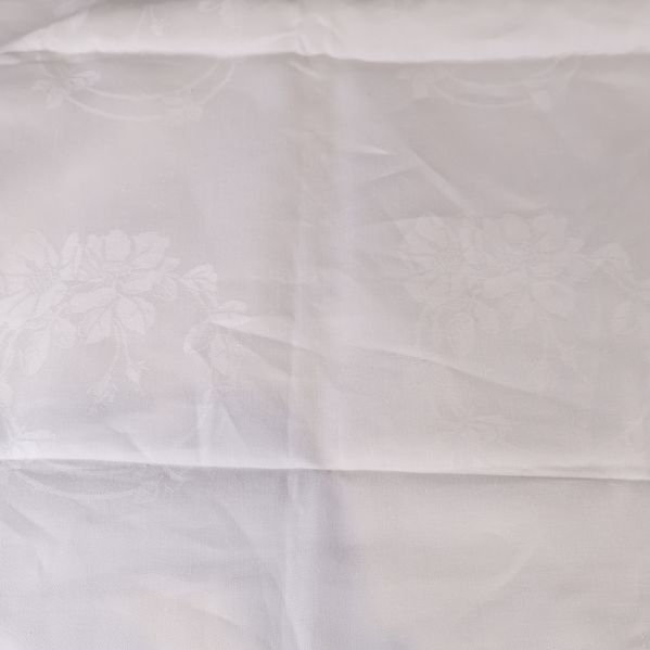 Bordsduk med subtila blommönster i tygstrukturen