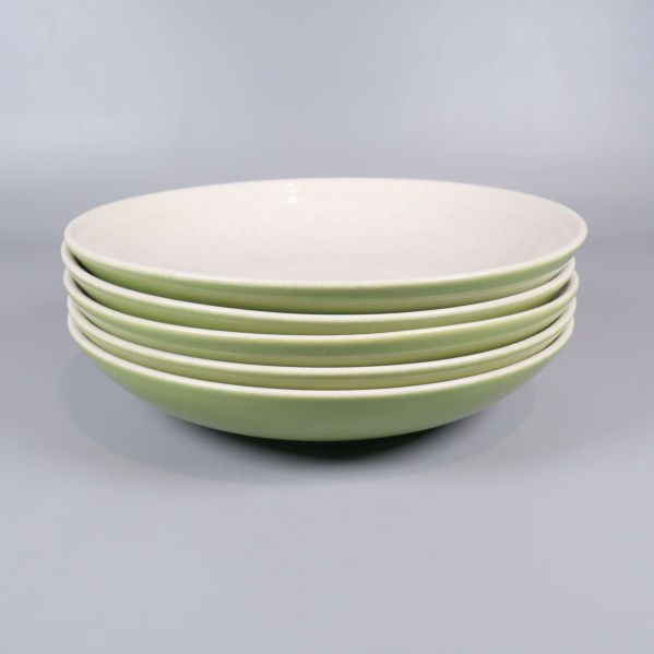 Staplade tallrikar visar grön utsida och vit insida