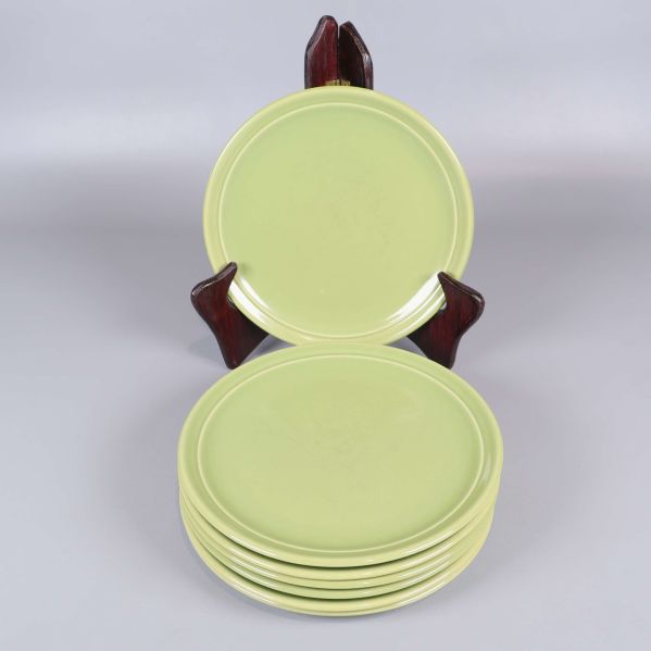 Sju gröna tallrikar, en uppställd och sex staplade