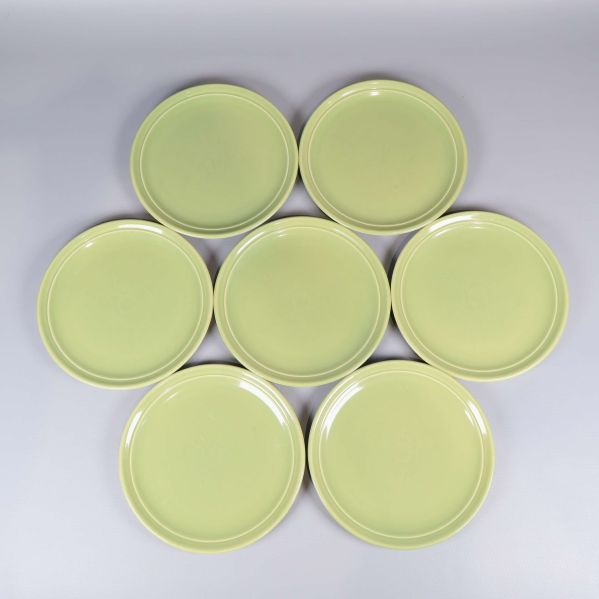 Sju gröna tallrikar ordnade i ett mönster sett uppifrån