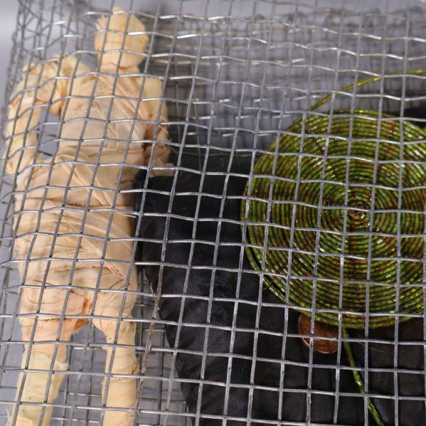 Närbild på figurdocka och grönt cirkulärt objekt i nätet