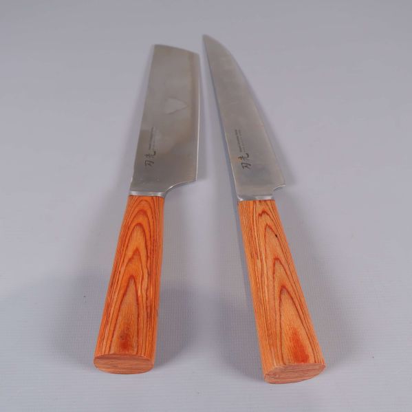 Två köksknivar uppackade med blad och träfärgade handtag