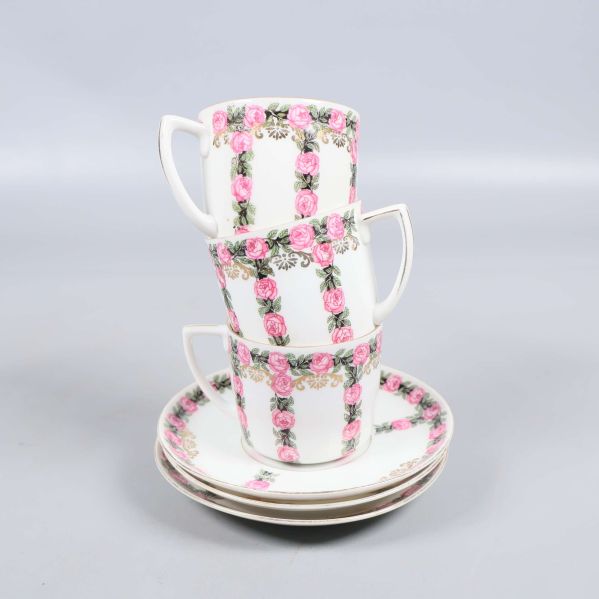 Tre staplade koppar med fat dekorerade med rosa rosor