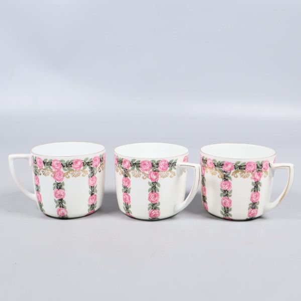 Tre koppar på rad med blommigt mönster och vita handtag