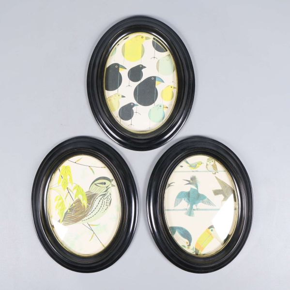 Tre ovala svarta ramar med olika motiv