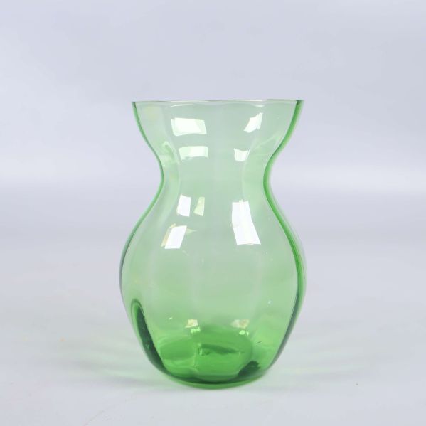 Grön vas i transparant glas på vit bakgrund