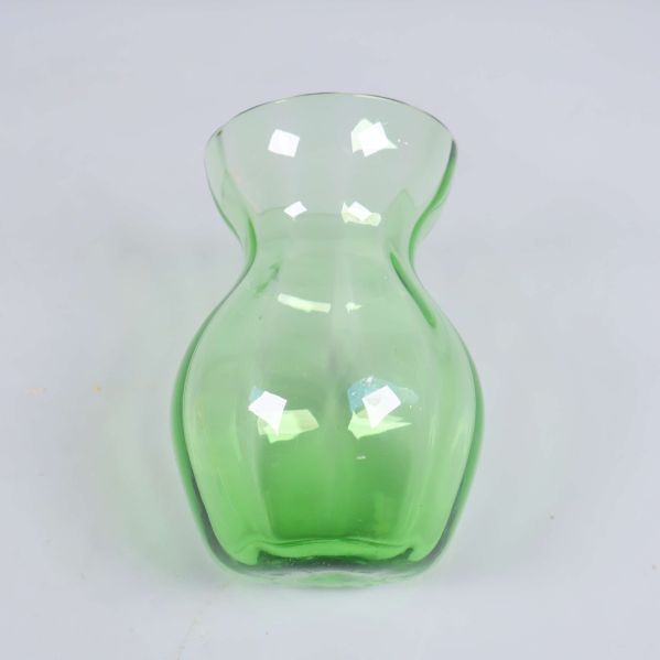 Grön vas i glas sedd framifrån på vit bakgrund