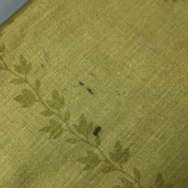 Fläckar synliga på grön textilyta av draperiet