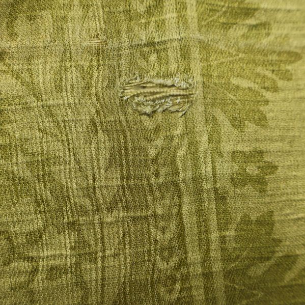 Närbild av mindre skada på draperiets textil