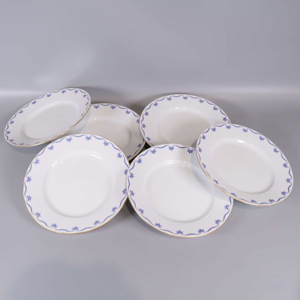 Sex tallrikar med blå dekor och guldkant utlagda