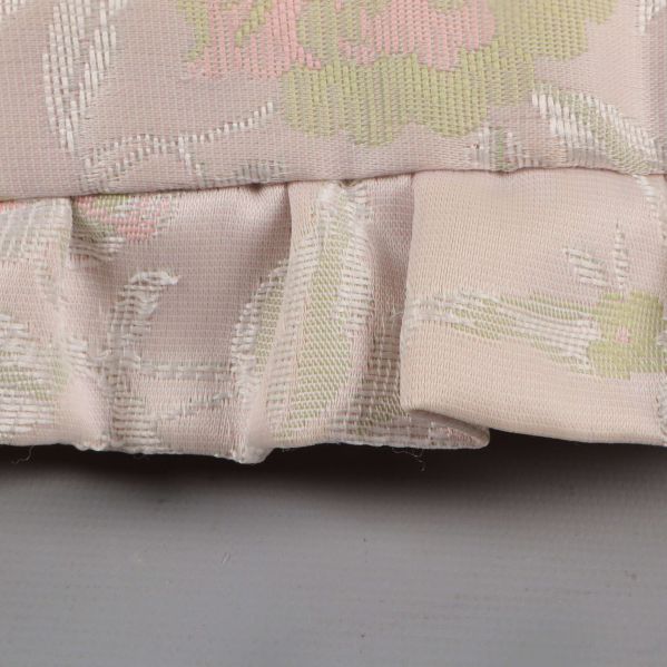 Närbild på volangkant och tygs struktur på kudde