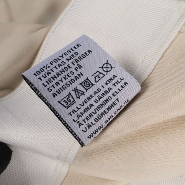 Materialetikett som visar 100% polyester och tvättråd