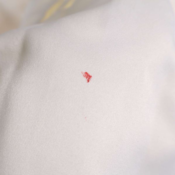 Närbild på röd fläck på vit gardin