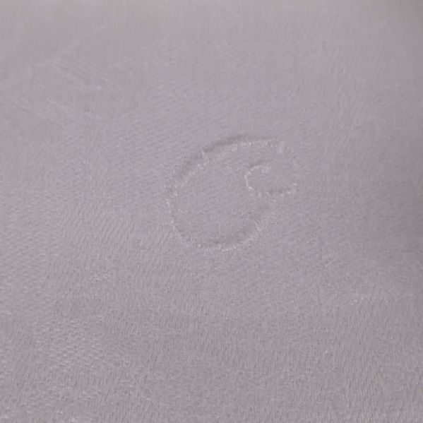 Detaljerad vävd märkning i vit duk