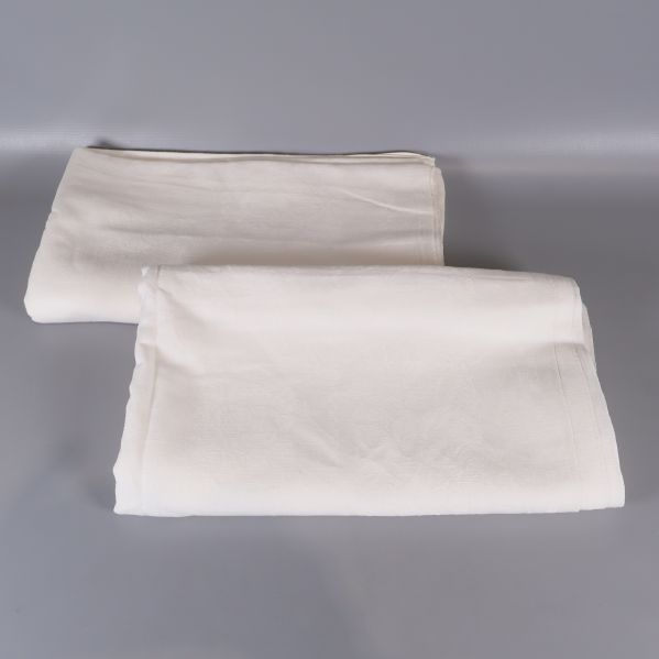 Två vikta vita dukar på ljus yta