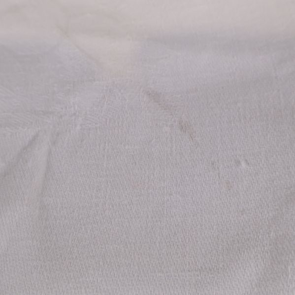 Fokus på mindre bruksspår och tygstruktur på vit duk