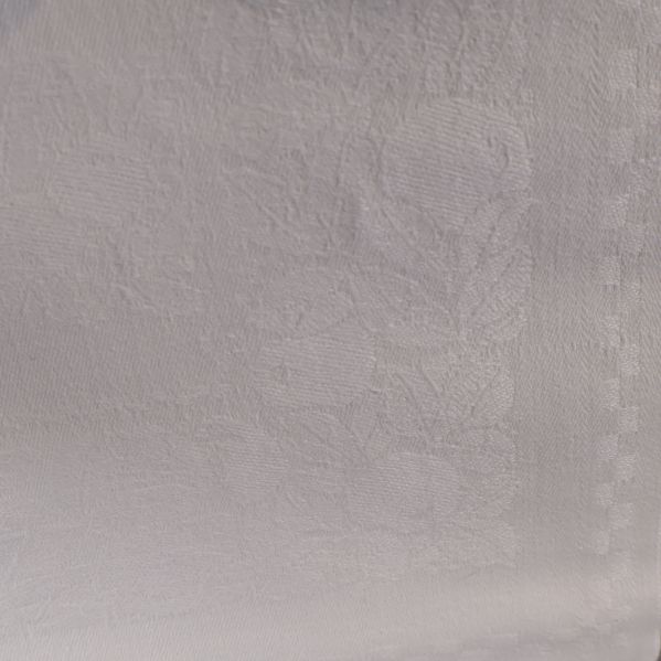 Närbild av vävt blommönster på vit duk