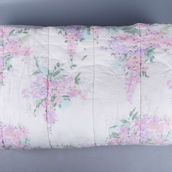 Täcke med blommigt pastellmönster utbrett på golvet