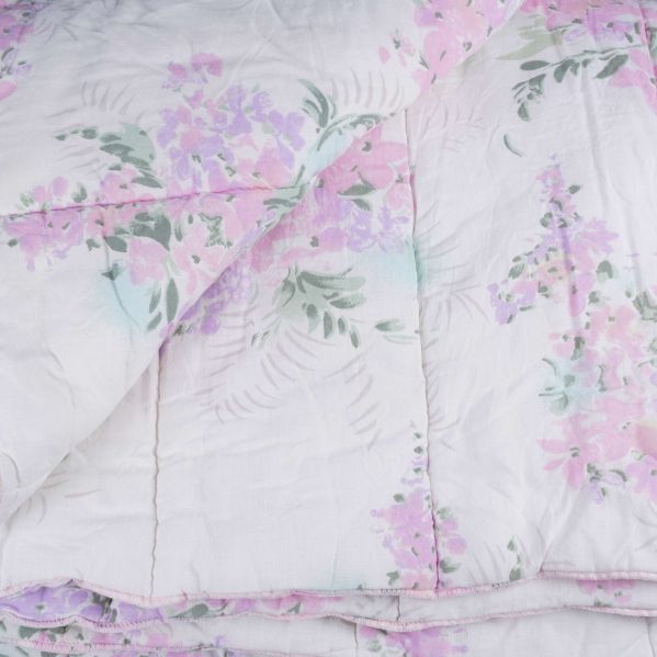 Närbild på täckets hörn med blommor i rosa och lila