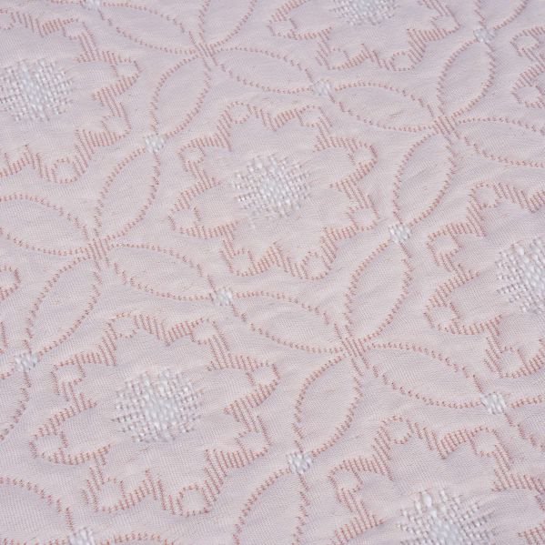 Närbild på quiltat blommönster i ljust tyg