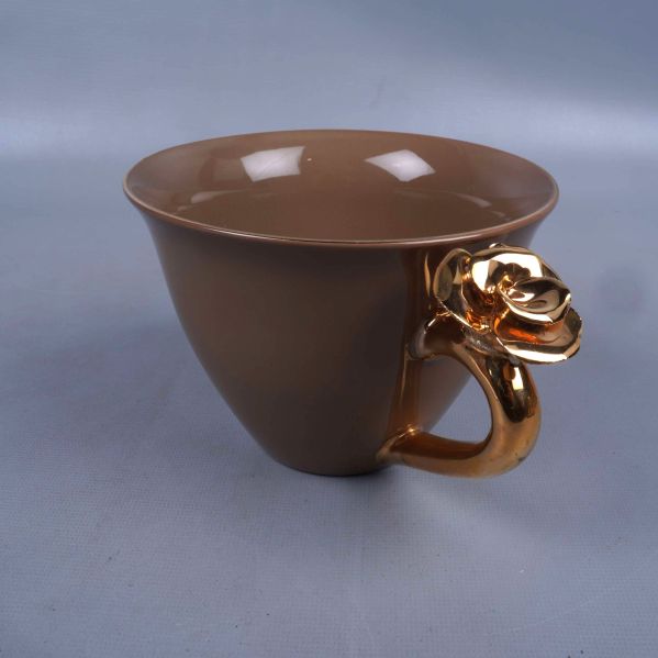 Brun kopp med detaljerat guldhandtag med blommdetalj