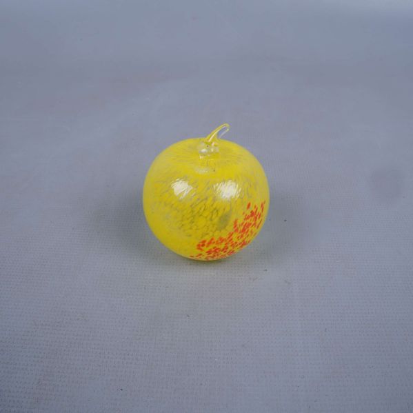 Gult glas äpple med orangea prickar, fotad ovanifrån