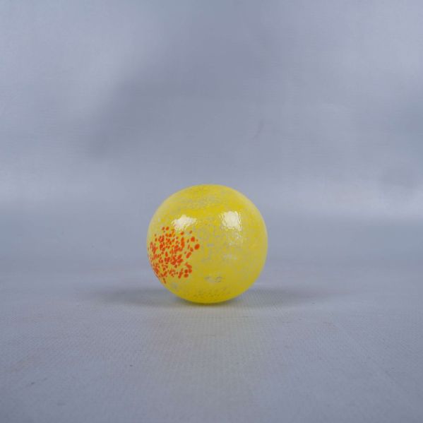 Gult glasäpple med orangea detaljer, sedd underifrån