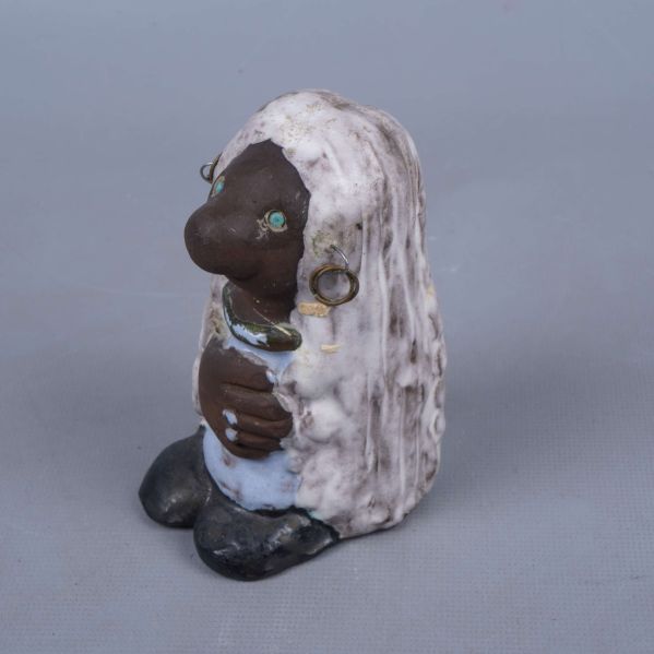 Sida av keramisk figur med örhängen och armband