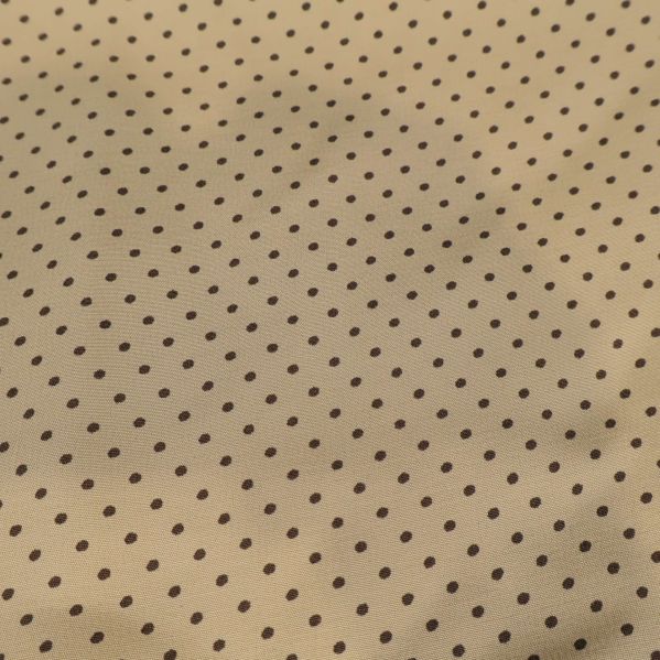 Närbild på beige tyg med små mörka prickar