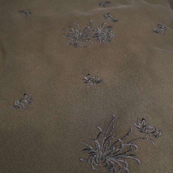 Närbild av broderade blommor på tyg