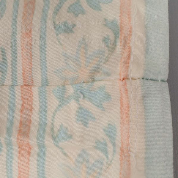 Närbild av gardinkant med synlig söm (två delar sydda ihop)