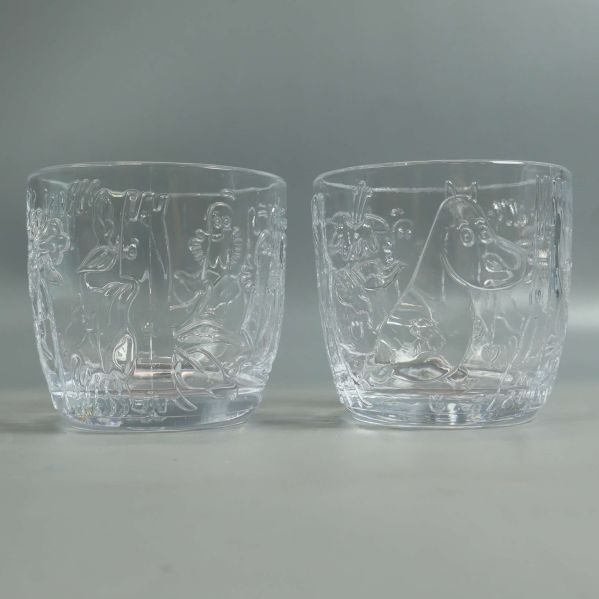 Framifrån: två Mumin-glas med reliefer