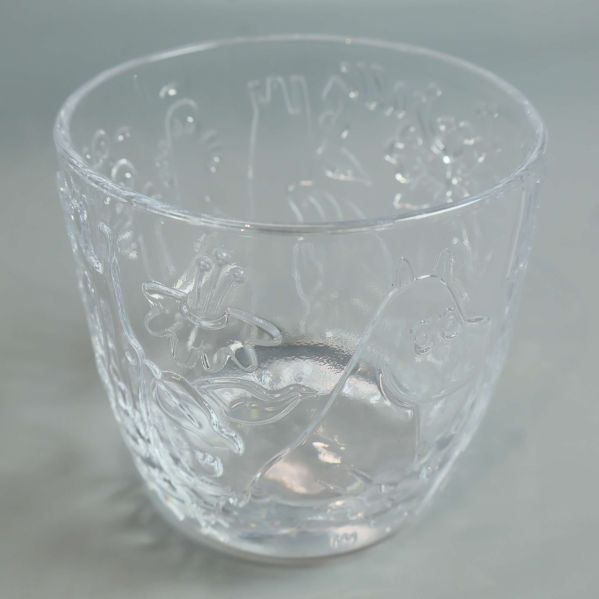 Närbild på ett genomskinligt glas med Muminmotiv