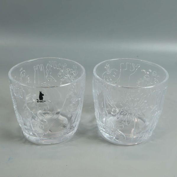 Två Mumin-glas med olika relieffigurer framtill