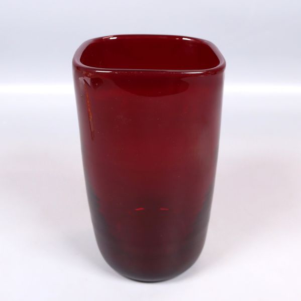 Röd glasvas sedd snett framifrån med fyrkantig öppning
