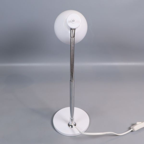Bordslampa sedd snett bakifrån med kromad arm