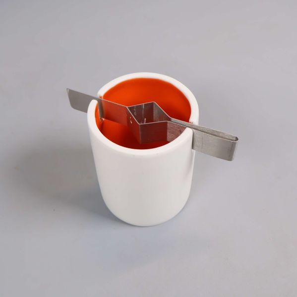 Närbild av rund ljuslykta med orange insida och metallhållare