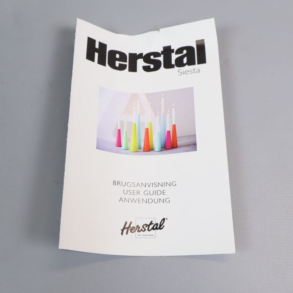 Manual med Herstal logotyp och ljusstakebilder på omslaget