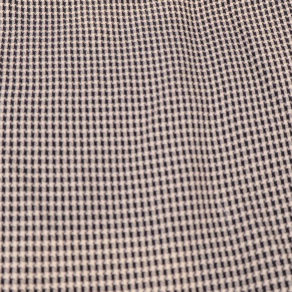 Närbild av smått rutigt tygmönster i beige och svart
