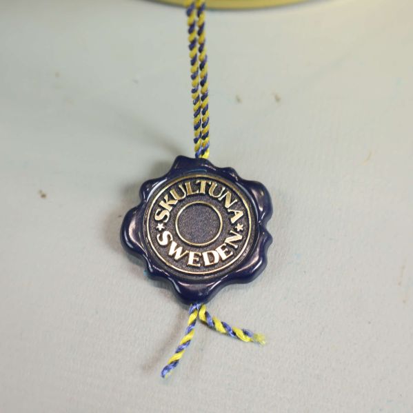 Närbild på Skultuna sigill hängande från burkens handtag