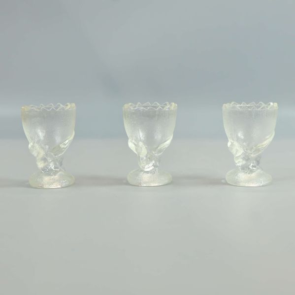 Tre äggkoppar i glas med dekorativa detaljer i närbild