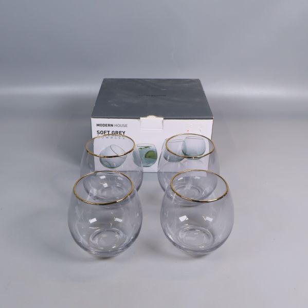 Fyra glas med guldkant framför originalförpackning