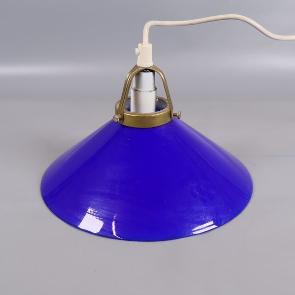 Närbild på blå glastaklampa med mässingsfäste